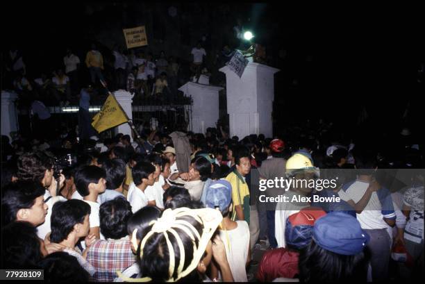 Supporters of opposition leader Cory Aquino invade the grounds of the Malacanang Palace, Manila, home of President Ferdinand Marcos, shortly after...