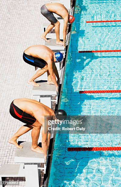 three swimmers on pool start blocks - race ethnicity stock pictures, royalty-free photos & images