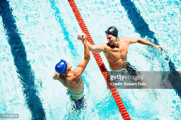 two swimmers in a pool joining hands - sports team high five stock pictures, royalty-free photos & images