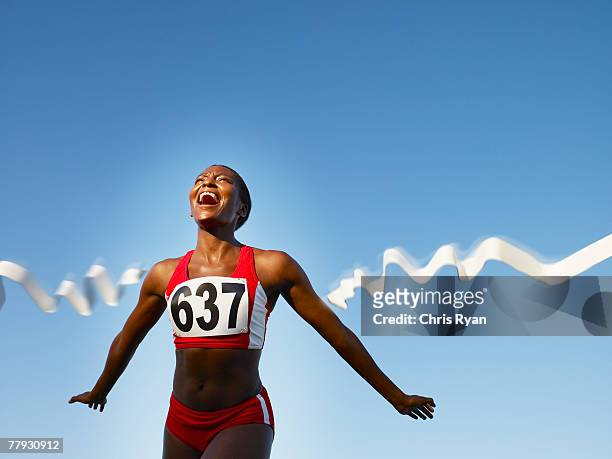racer de cruzar la línea de meta sonriendo - athlet fotografías e imágenes de stock