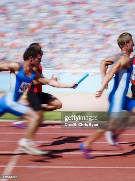 racers running on track with relay baton - estafette stockfoto's en -beelden