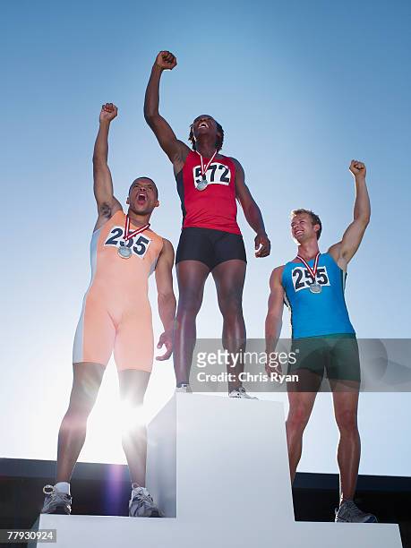 podium with three winning athletes cheering on it - sportsperson medal stock pictures, royalty-free photos & images