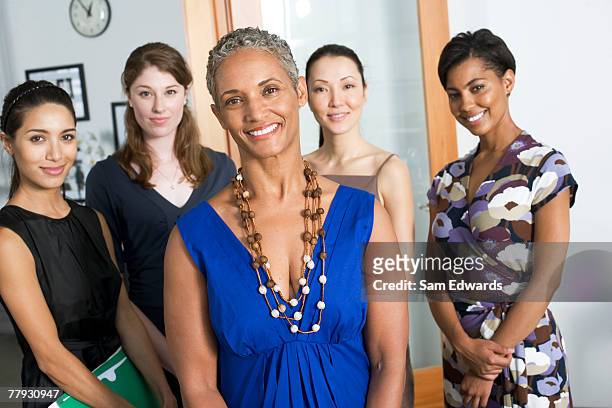 group of businesswomen in an office smiling - minority groups professional stock pictures, royalty-free photos & images