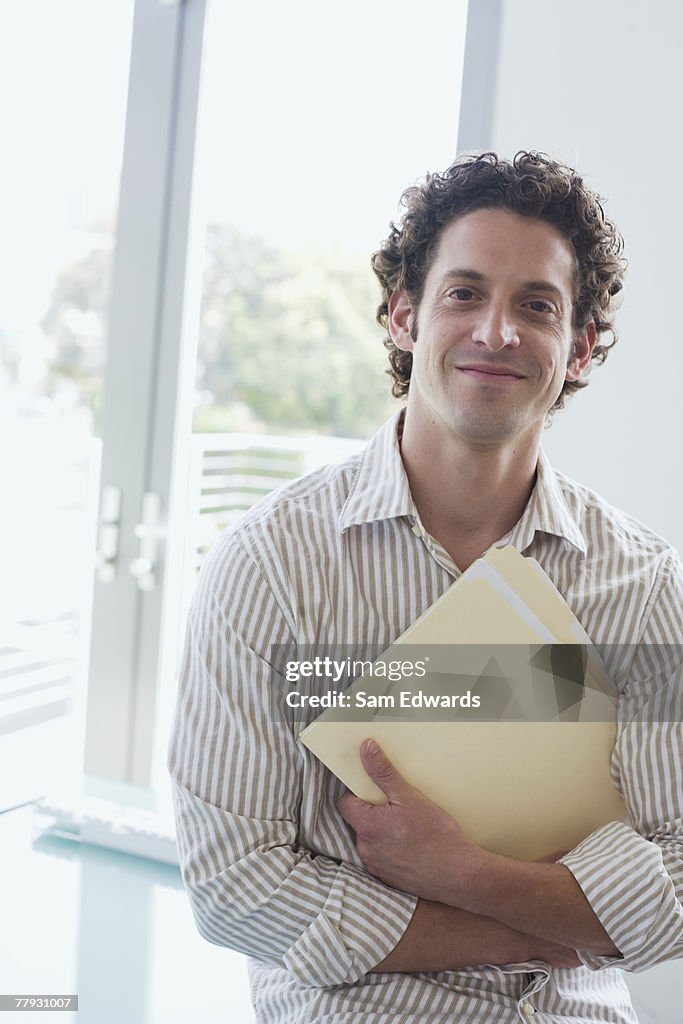 Businessman holding folder in arms in office