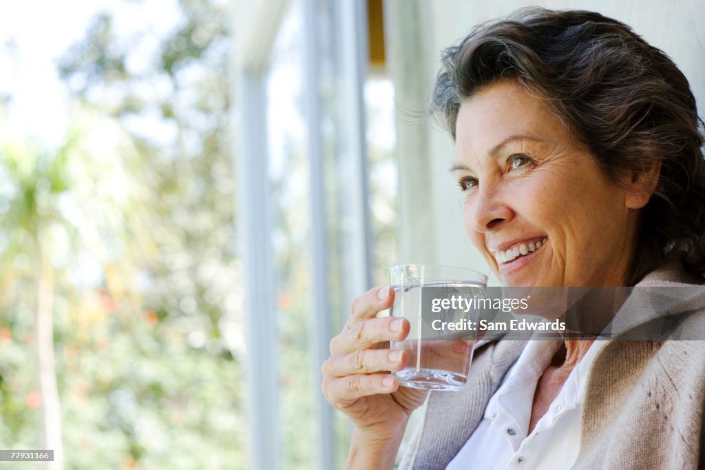 Woman with glass of water standing in doorway