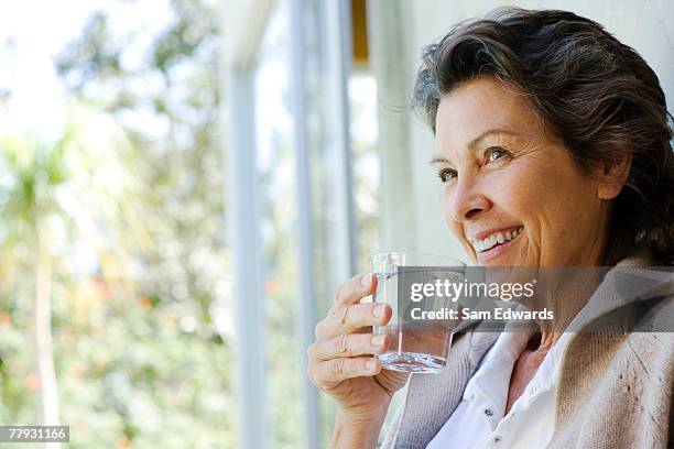 woman with glass of water standing in doorway - drinking water stock pictures, royalty-free photos & images