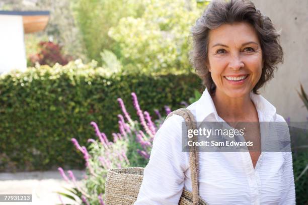 woman outside home with large purse smiling - 60 woman stock pictures, royalty-free photos & images