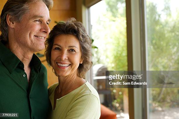 couple in modern home by large window - 50 54 years stock pictures, royalty-free photos & images