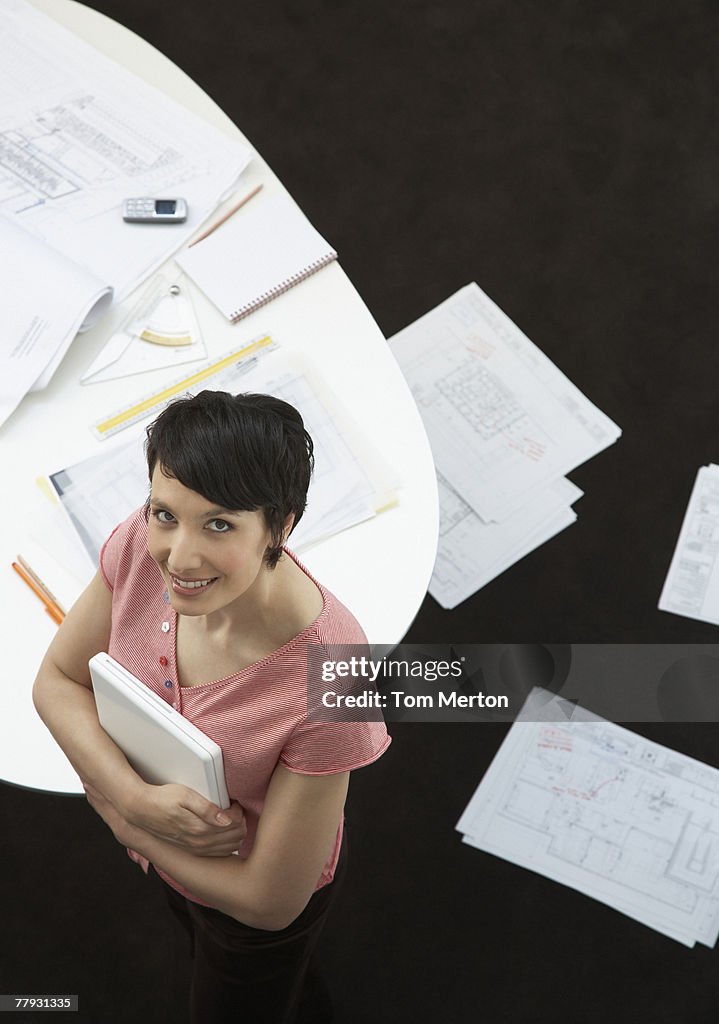 Businesswoman holding laptop with paperwork on floor