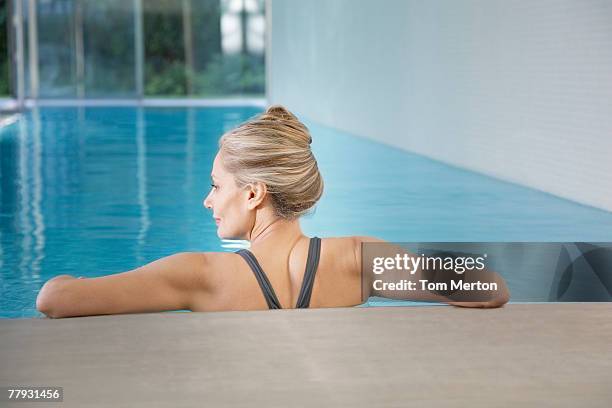 woman leaning against an indoor pool ledge relaxed - older woman bathing suit stock pictures, royalty-free photos & images