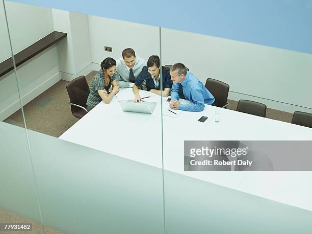 four businesspeople at a table with documents and laptop - four people stock pictures, royalty-free photos & images