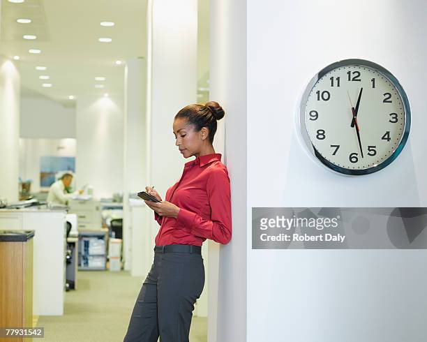 businesswoman in office using pda near a clock - clock person desk stockfoto's en -beelden