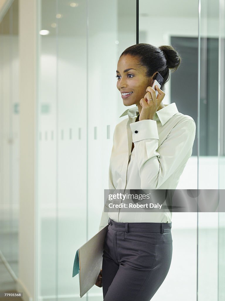 Businesswoman on her mobile phone in office hallway