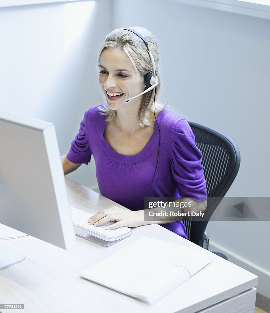 Businesswoman wearing a headset at her desk smiling