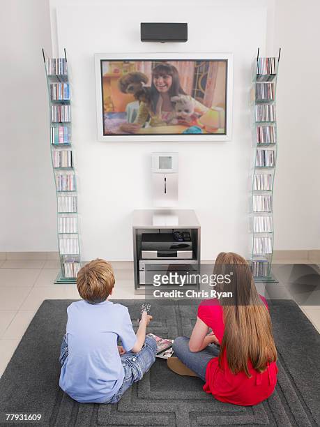 jeune garçon et fille regardant la télévision - command sisters photos et images de collection