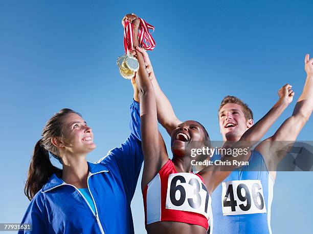 three athletes holding medals up over their heads - medalist stock pictures, royalty-free photos & images