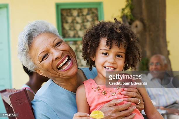 woman and young girl outdoors with people in background - granddaughter stock pictures, royalty-free photos & images