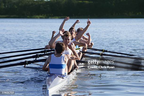 athletes in a crew row boat cheering - sportteam stockfoto's en -beelden