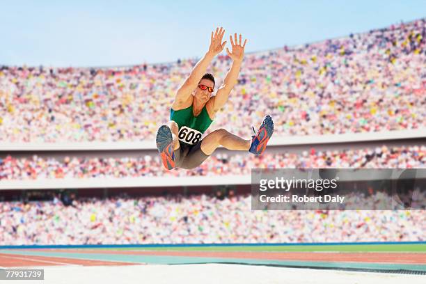athlete doing a long jump in an arena - long jump stock pictures, royalty-free photos & images