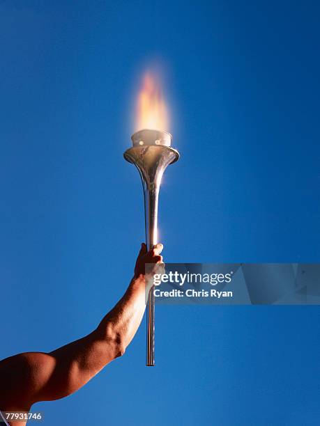 athlete's arm holding up a torch - fakkel stockfoto's en -beelden