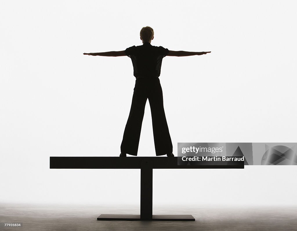 Mulher em pé numa tábua com os braços esticados
