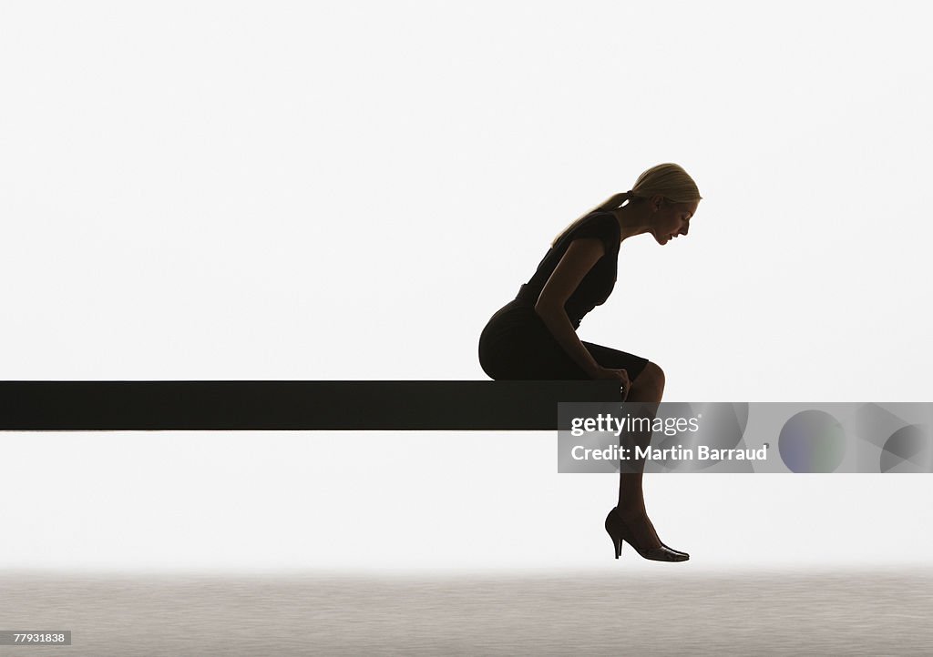 Woman sitting on a plank looking over ledge