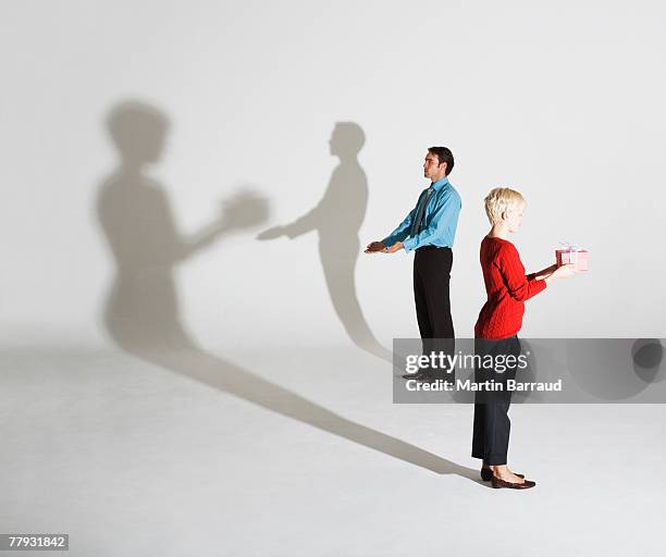 businessman and woman standing so shadows look like she's giving him a gift - delusione stock pictures, royalty-free photos & images