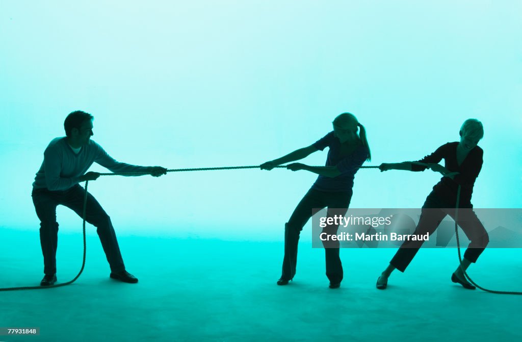 Man and two women playing tug of war