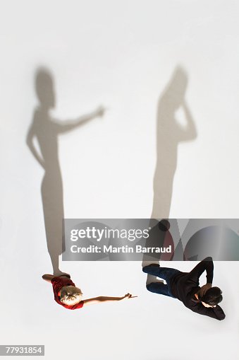 Woman pointing at man facing away from her Woman pointing at man facing away from her