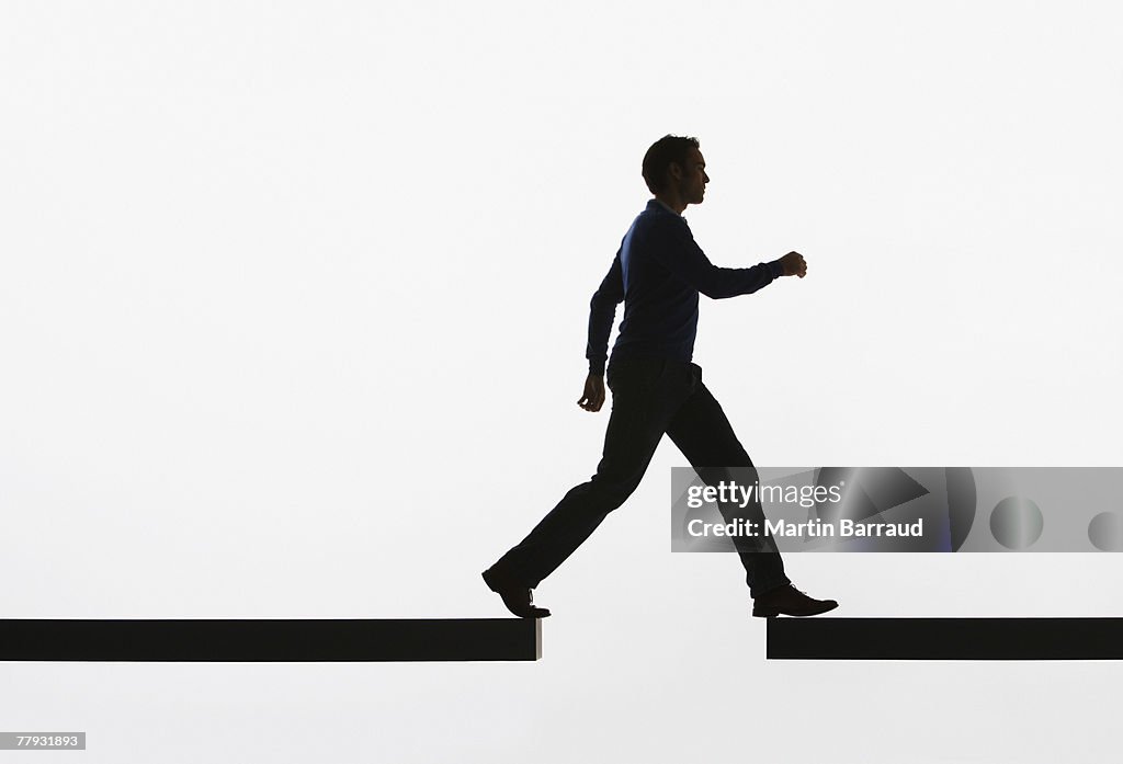 Man walking from a plank onto another plank