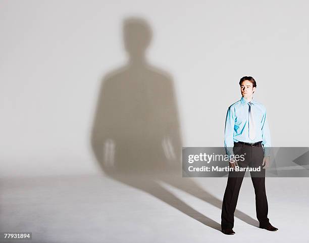 businessman standing with arms by sides - person shadow stock pictures, royalty-free photos & images