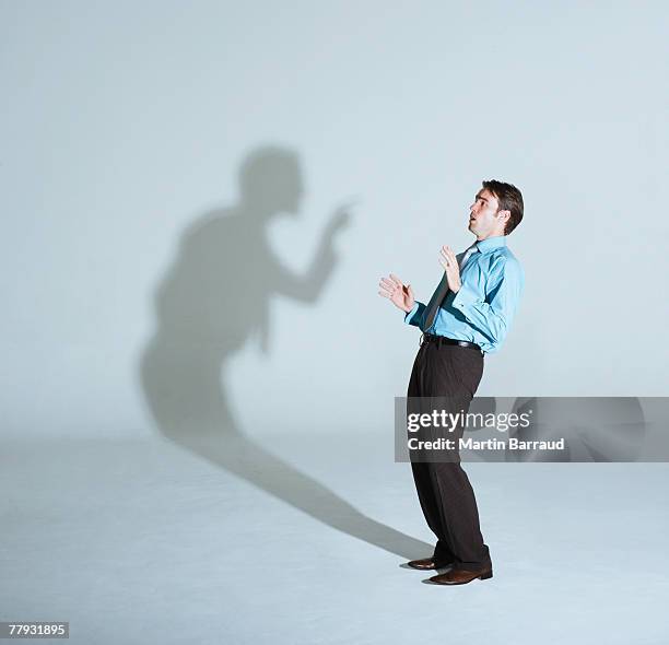 businessman being scolded by his shadow - delusione stock pictures, royalty-free photos & images