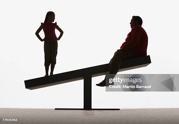 large man and small girl on unbalanced plank - fat silhouette stockfoto's en -beelden