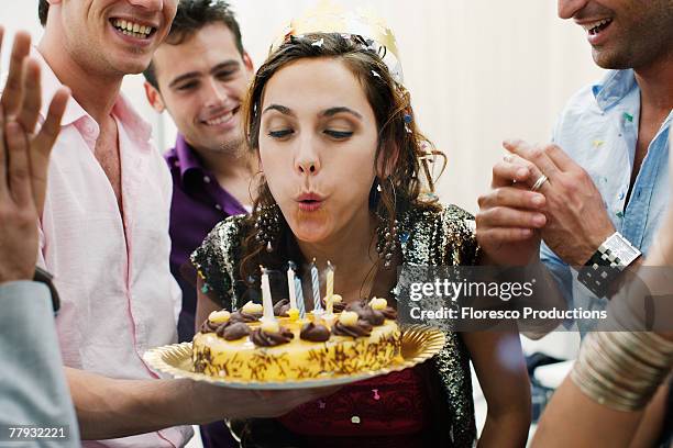 woman blowing out candles on birthday cake - vela de cumpleaños fotografías e imágenes de stock