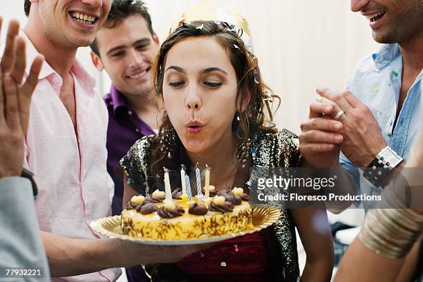 woman blowing out candles on birthday cake - candeline di compleanno foto e immagini stock