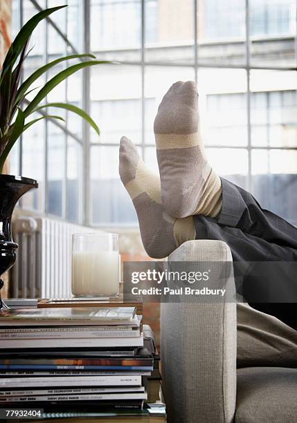 mann's füße auf arm der couch in moderne zuhause - legs crossed at ankle stock-fotos und bilder