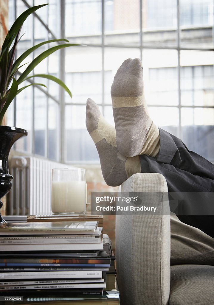 Man's feet up on arm of couch in modern home