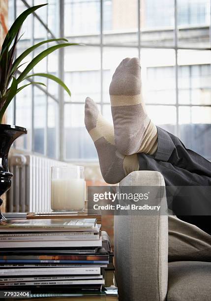 man's feet up on arm of couch in modern home - feet up 個照片及圖片檔