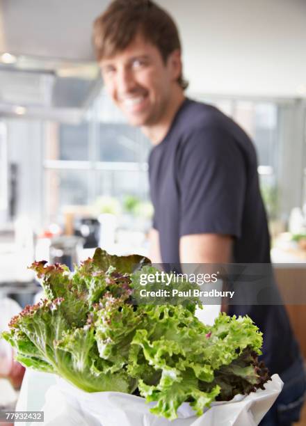 lettuce in a bag with man in background - young man groceries kitchen stock pictures, royalty-free photos & images