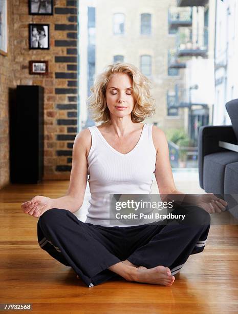 woman doing yoga in living room - meditation concentration stock pictures, royalty-free photos & images