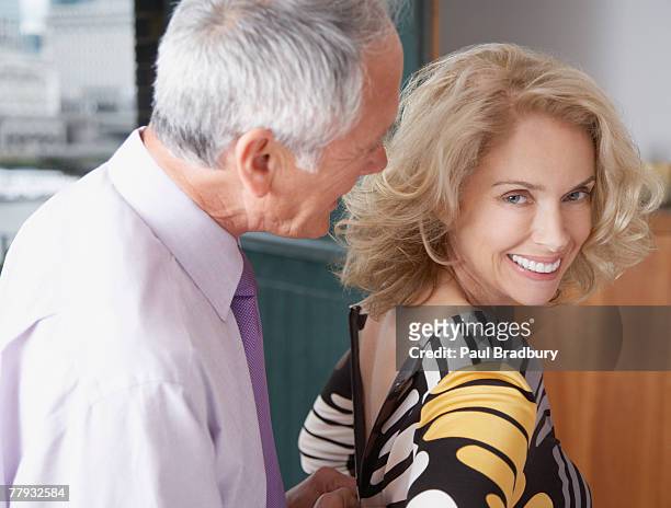 hombre ayudando a mujer con vestido con cremallera - romance de oficina fotografías e imágenes de stock