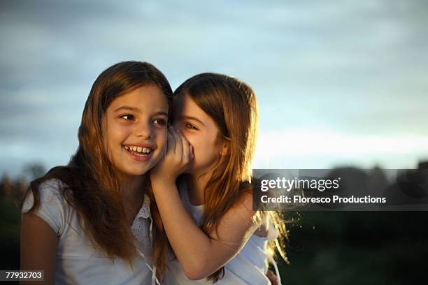 girl whispering in other girl's ear - child whispering stock-fotos und bilder