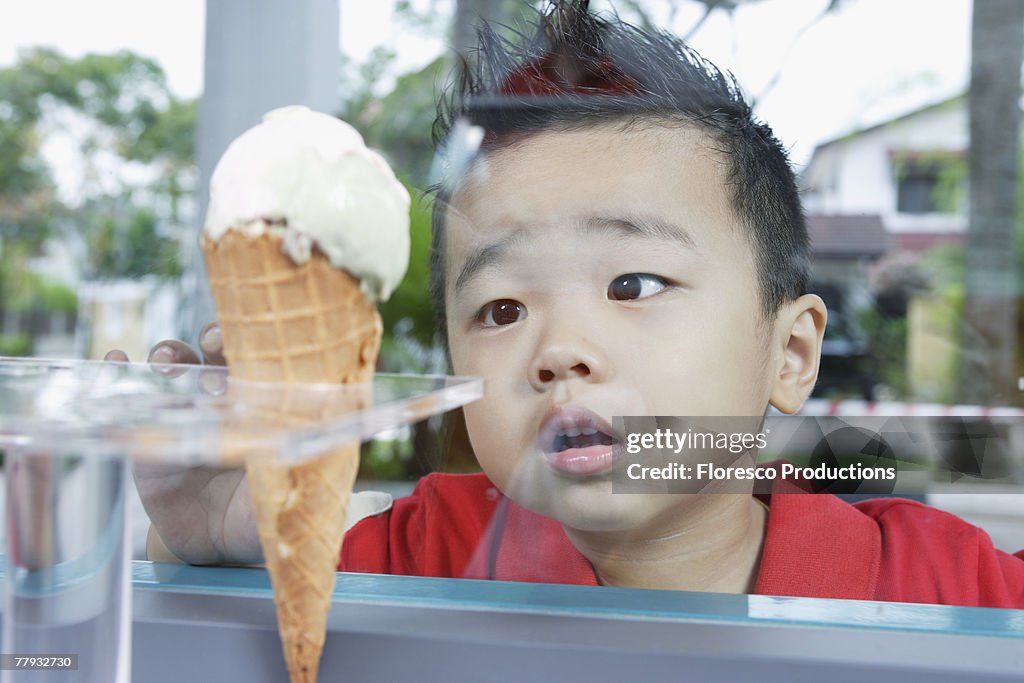 Boy looking at ice cream cone through glass