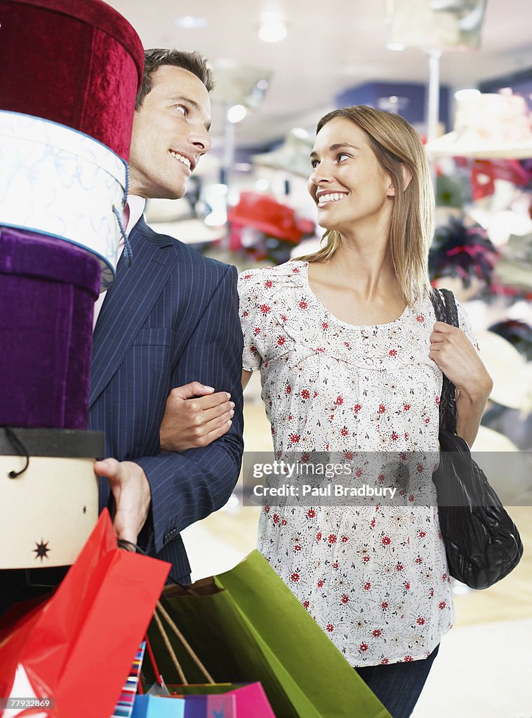 Couple en magasin avec chapeau les boîtes et sacs de courses