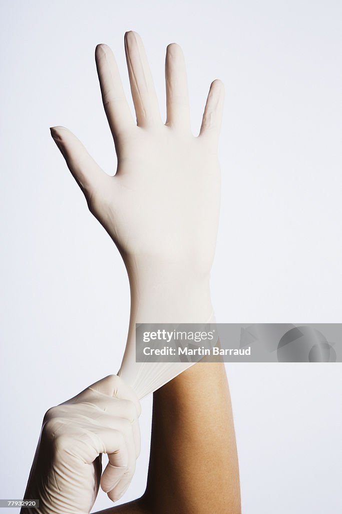 Two hands putting latex gloves on