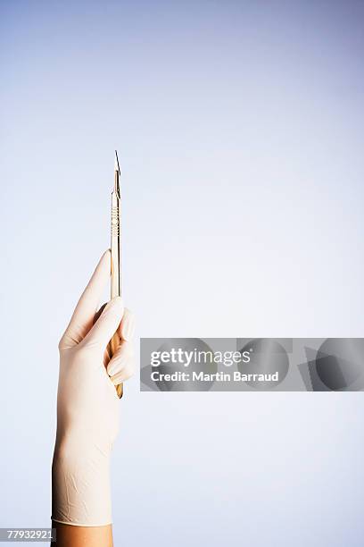 a gloved hand holding a scalpel - scalpel stock pictures, royalty-free photos & images