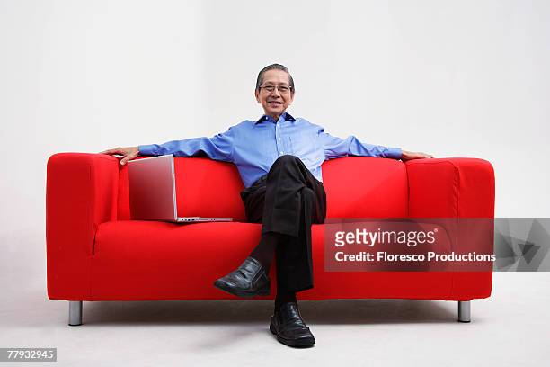man sitting on sofa with laptop - man sitting on sofa fotografías e imágenes de stock