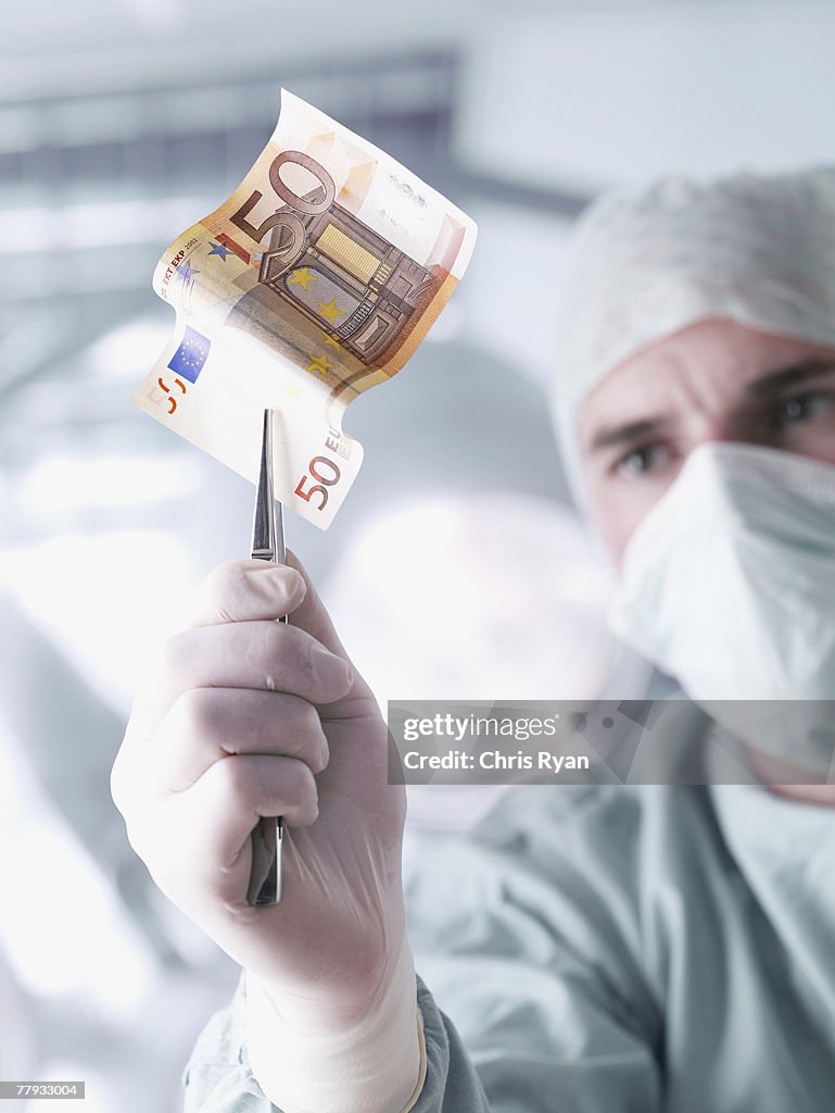 Doctor holding a fifty euro banknote with tweezers