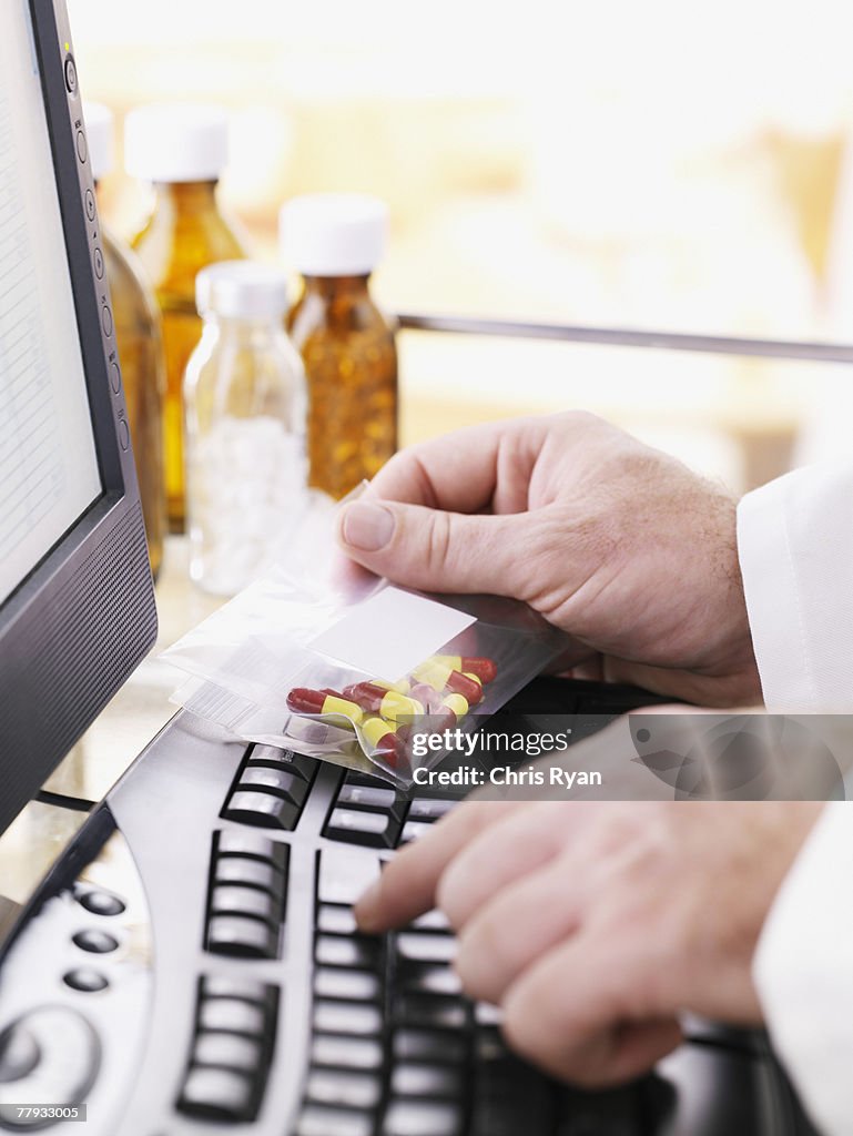 Medico con borsa di pillole al computer