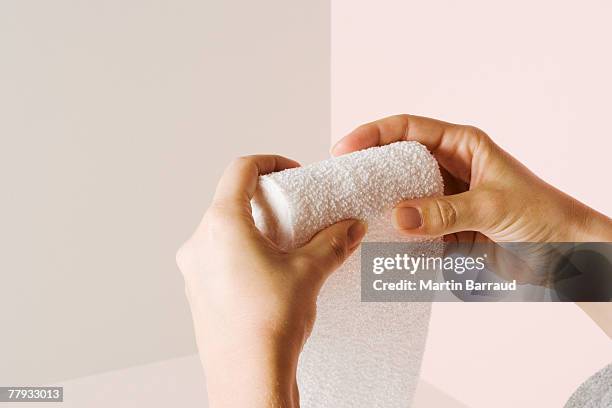 a roll of gauze sitting being rolled back up by two hands - bandage bildbanksfoton och bilder